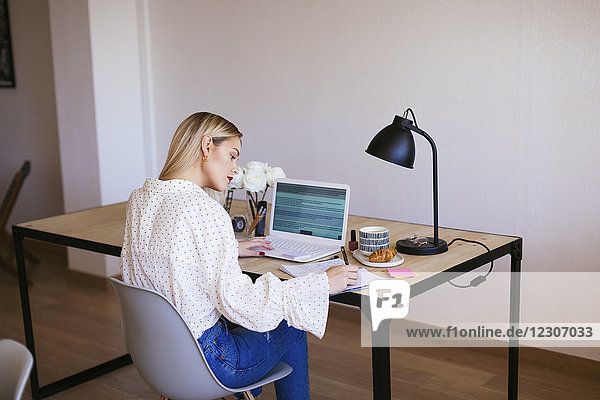 Blonde Geschäftsfrau am Schreibtisch sitzend  arbeitend