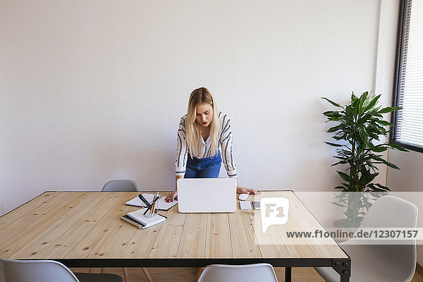 Junge Geschäftsfrau am Schreibtisch stehend  mit Laptop