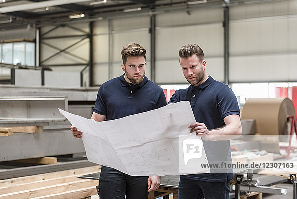 Two men looking at plan in factory