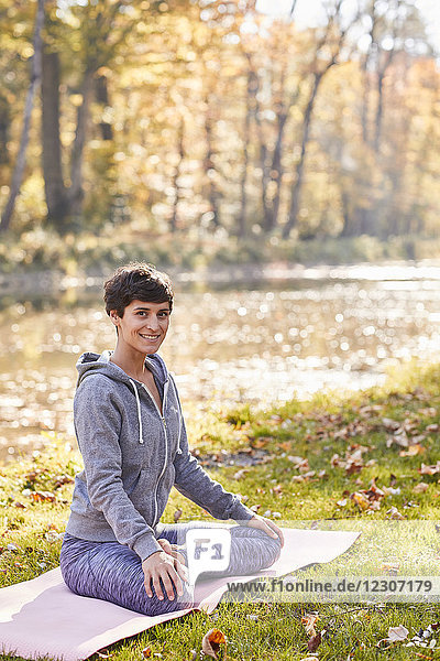 Lächelnde mittlere erwachsene Frau im Wald  die Yoga praktiziert  Lotusstellung