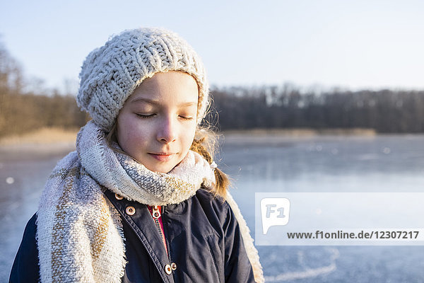 Deutschland  Brandenburg  Straussee  Portrait eines Mädchens auf gefrorenem See  Augen geschlossen