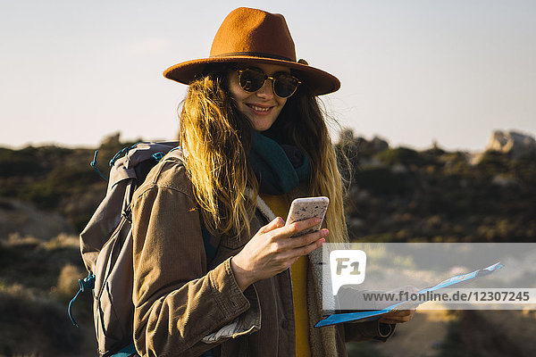 Italien  Sardinien  lächelnde Frau auf Wanderung mit Handy und Karte