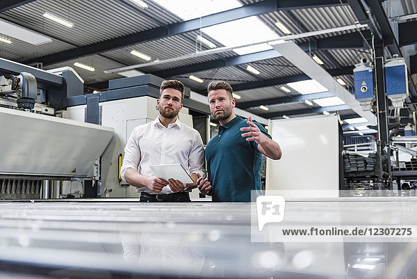 Two men with tablet discussing on factory shop floor