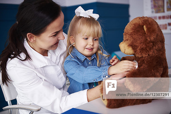 Arzt und Mädchen untersuchen Teddy in der Arztpraxis