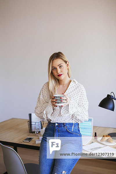 Young woman working in office  taking a break  drinking coffee