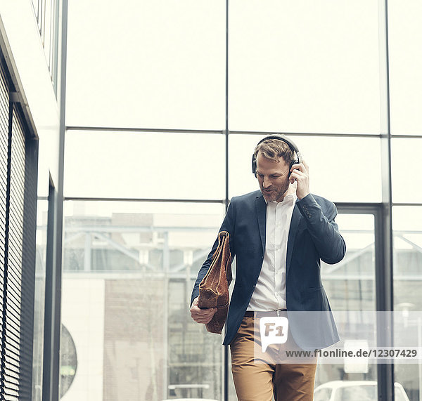 Smiling businessman listening to music with headphones