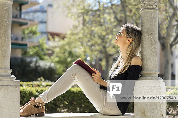Junge Frau mit Notizbuch entspannt auf der Bank