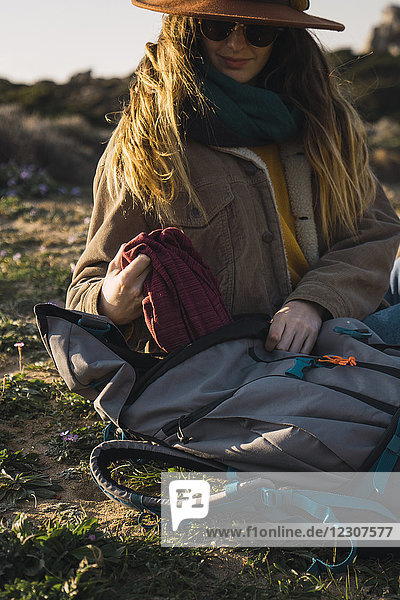 Italien  Sardinien  Frau auf einer Wanderung  die eine Pause macht und etwas aus dem Rucksack nimmt