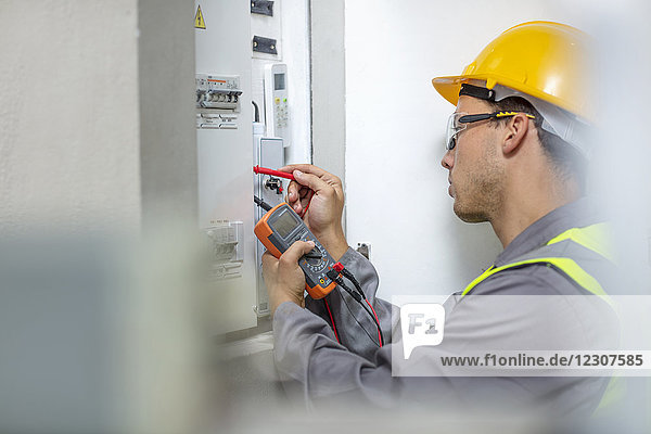 Electrician working with voltmeter at fusebox