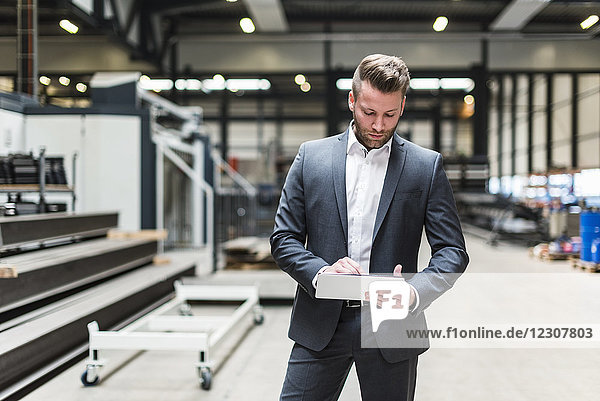 Businessman with tablet standing on factory shop floor