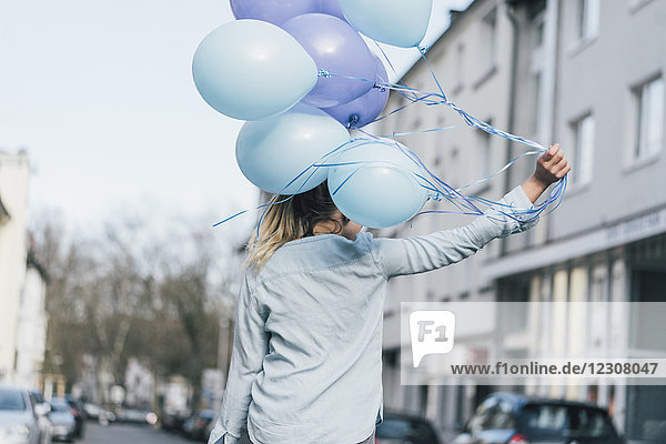 Rückansicht der Frau mit blauen Luftballons
