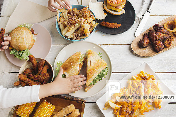 Children's hands on table full of American food
