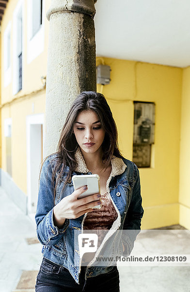 Young woman in a town checking her smartphone