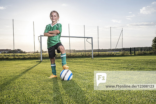 Porträt eines selbstbewussten jungen Fußballspielers mit Ball auf dem Fußballplatz
