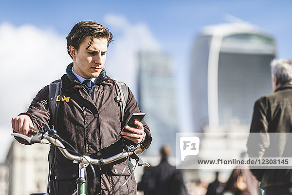 UK  London  Geschäftsmann mit Fahrrad auf dem Handy