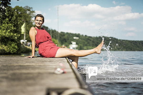 Glückliche Frau sitzt am Steg am See