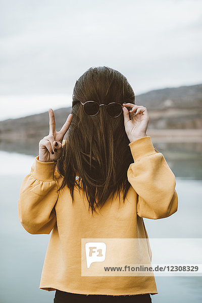Funny 'portrait' of young woman with sunglasses showing victory sign