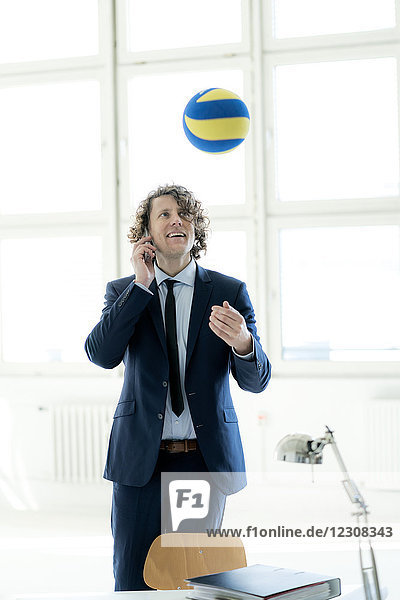 Businessman playing with a ball in his office  while talking on the phone