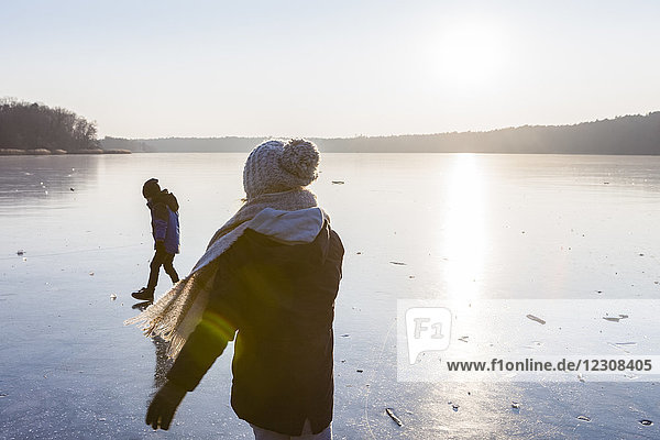 Germany  Brandenburg  Lake Straussee  two kids walking on frozen lake
