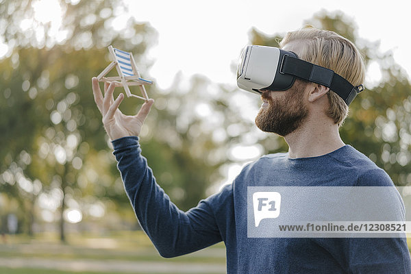 Mann im herbstlichen Park mit Virtual Reality Brille auf Mini-Strandliege