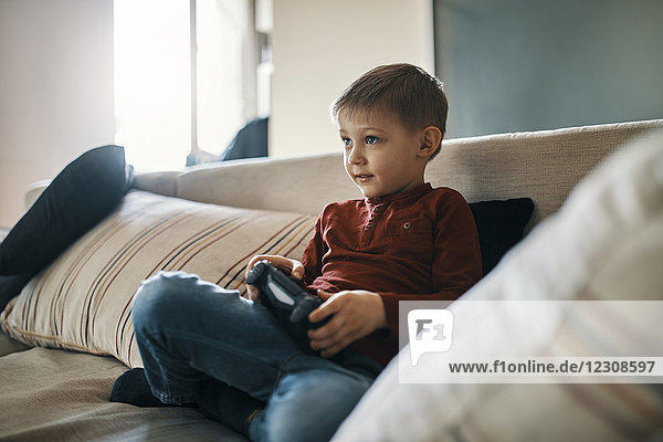 Portrait of little boy sitting on the couch playing computer game