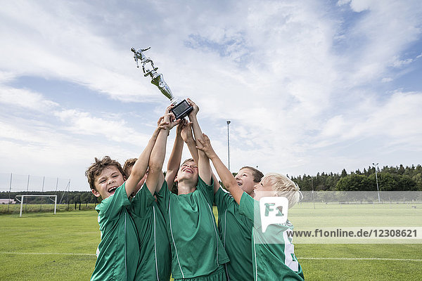 Junge Fußballspieler jubeln mit Pokal