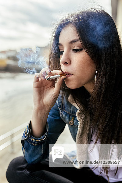 Junge Frau raucht eine Zigarette im Freien
