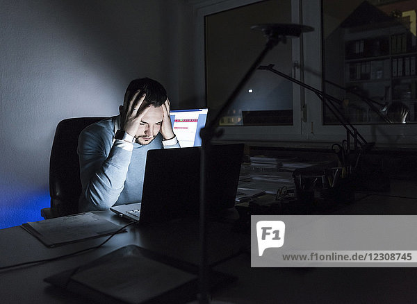 Müde Geschäftsleute sitzen nachts im Büro am Schreibtisch
