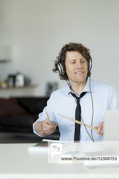 Businessman wearing headphones and drumming on his desk