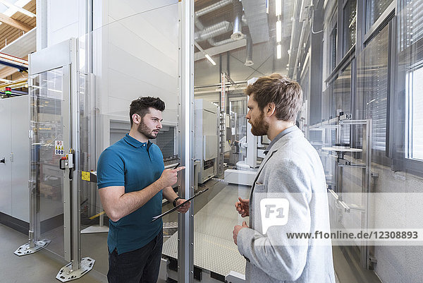 Businessman and employee discussing in modern factory