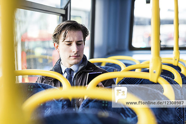 UK  London  Porträt eines Geschäftsmannes  der im Bus sitzt und auf sein Handy schaut.