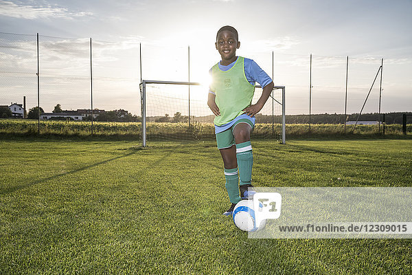 Porträt eines selbstbewussten jungen Fußballspielers mit Ball auf dem Fußballplatz