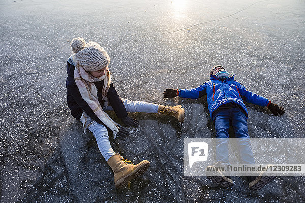 Deutschland  Brandenburg  Straussee  zwei Kinder sitzend und liegend auf dem zugefrorenen See