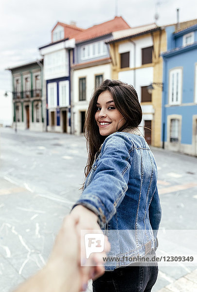 Porträt einer lächelnden  brünetten Frau  die in einer Stadt die Hand hält.