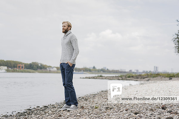 Deutschland  Düsseldorf  entspannter Mann steht am Flussufer und schaut auf die Aussicht