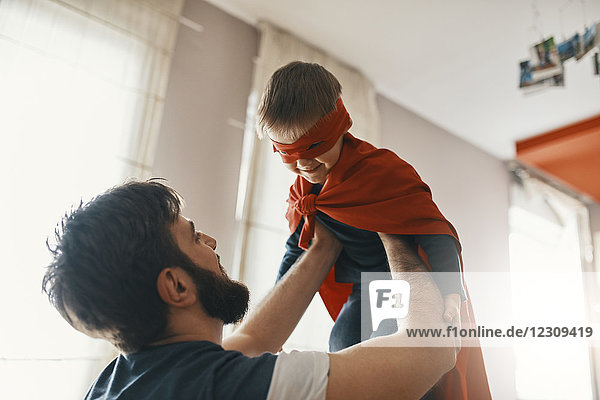 Vater spielt mit seinem kleinen Sohn  verkleidet als Superheld.