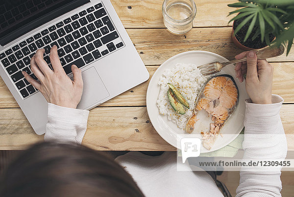 Frau beim Mittagessen und Laptopbenutzung