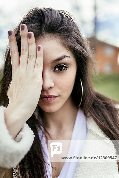Portrait of a beautiful brunette woman covering an eye