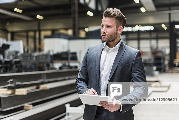Businessman using tablet on factory shop floor