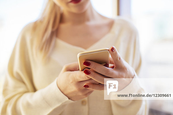 Blonde woman using smartphone at home