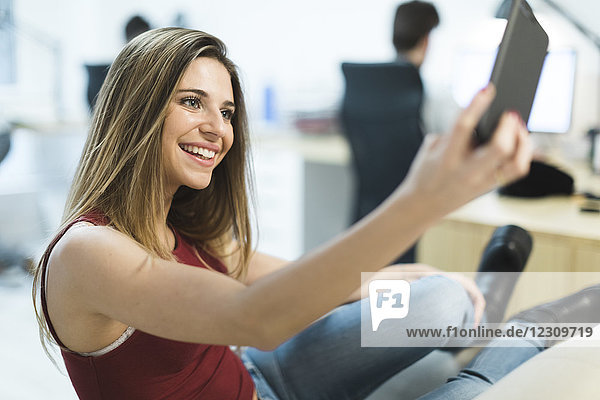 Lächelnde junge Frau mit Handy im Büro
