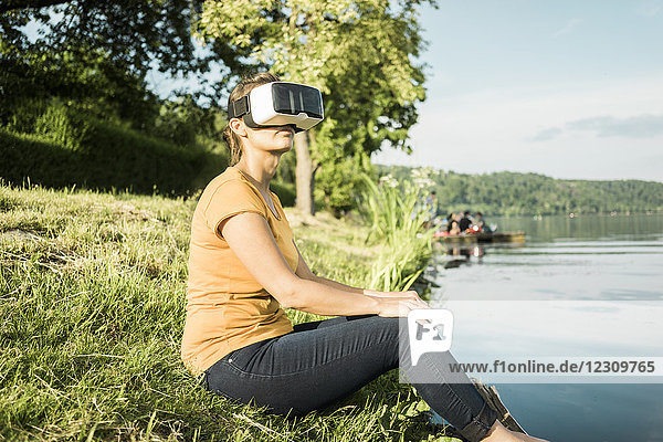 Frau am See sitzend mit VR-Brille