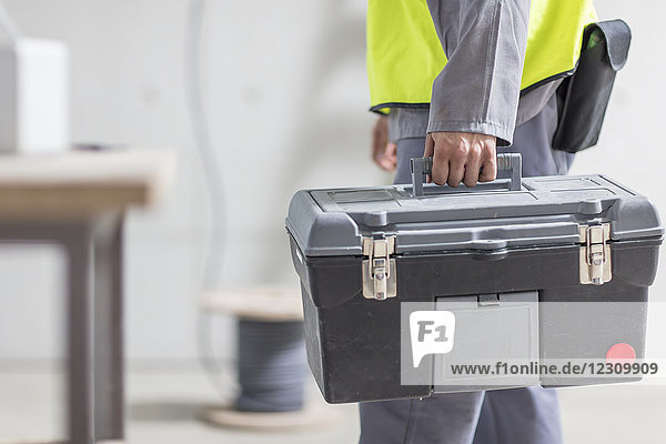 Close-up of construction worker carrying tool box