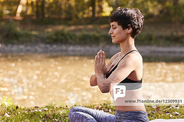 Mittlere erwachsene Frau am Flussufer praktiziert Yoga  Meditation