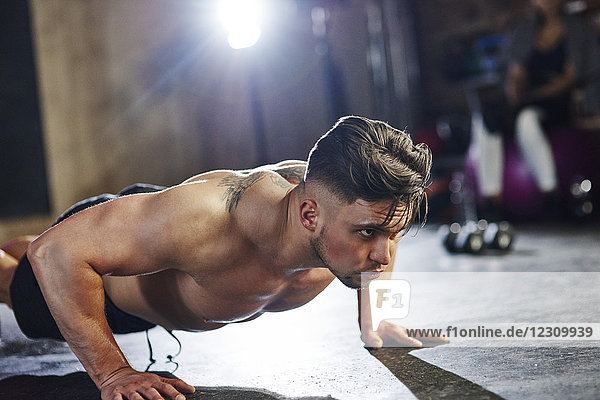 Ernsthafter Mann der Liegestütze im Fitnessstudio macht.