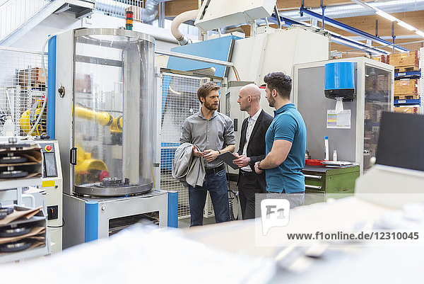 Businessman and employees discussing in modern factory
