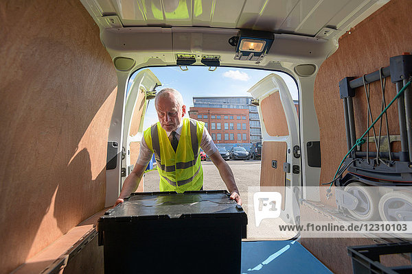 Älterer Auslieferungsfahrer belädt alle Elektro-Lieferwagen