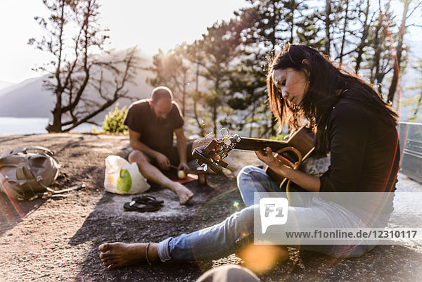 Man and woman relaxing  cooking food and playing guitar on The Malamute  Squamish  Canada