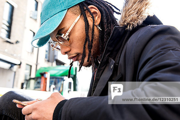 Man with dreadlocks looking at smartphone
