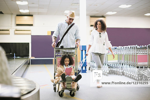 Familie mit Mädchen auf Gepäckwagen im Flughafen